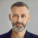 Portrait of confident attractive senior European business man looking at camera with friendly face expression on gray studio background. Head shot of happy mature bank client or barbershop customer